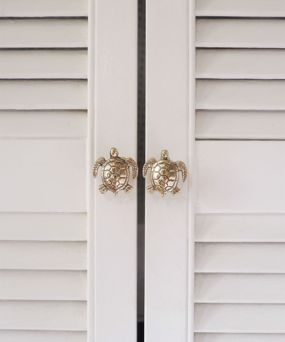 Twee witte louvre kastdeurtjes met deurknopjes in de vorm van een messing schildpad