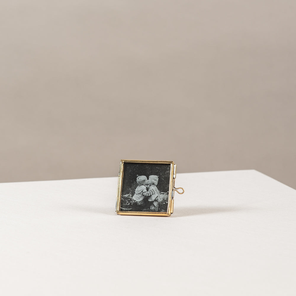 Mini fotolijstje van goud metaal en glas, met daarin een zwartwit foto van 2 kleine kindjes