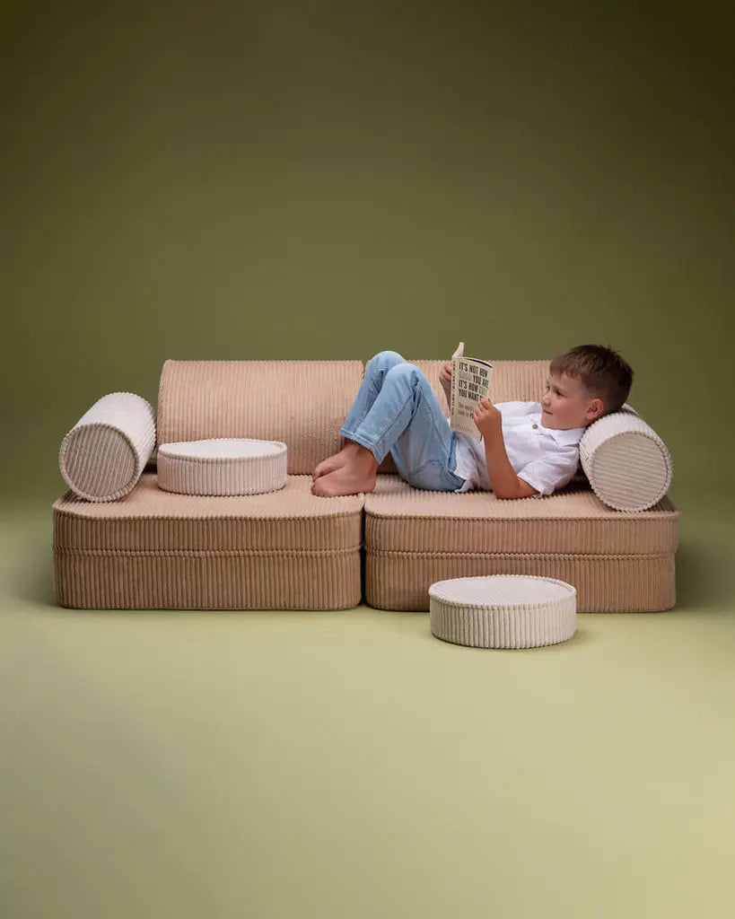 Jongetje ligt op de modulaire bank voor de kinderkamer. Van Wigiwama, in beige en creme