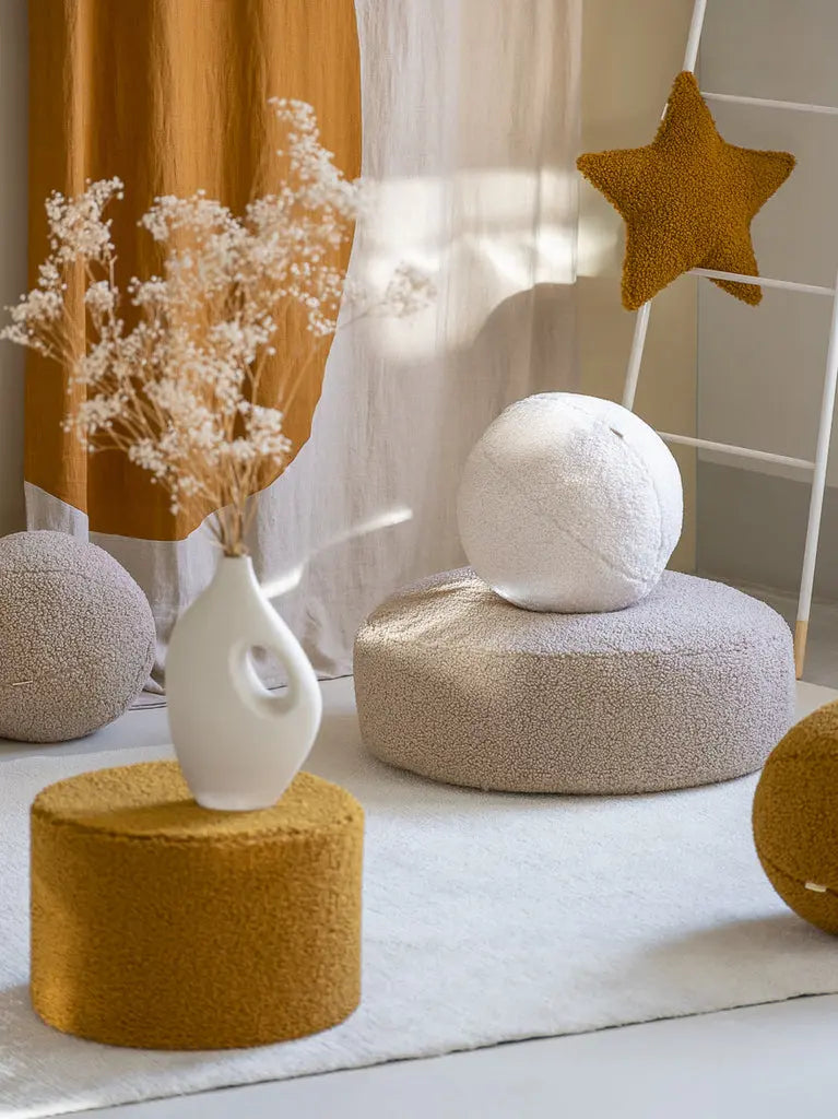 Sfeerbeeld van de Wigiwama serie met teddy stof, poefs en kussens in beige, wit en okergeel.
