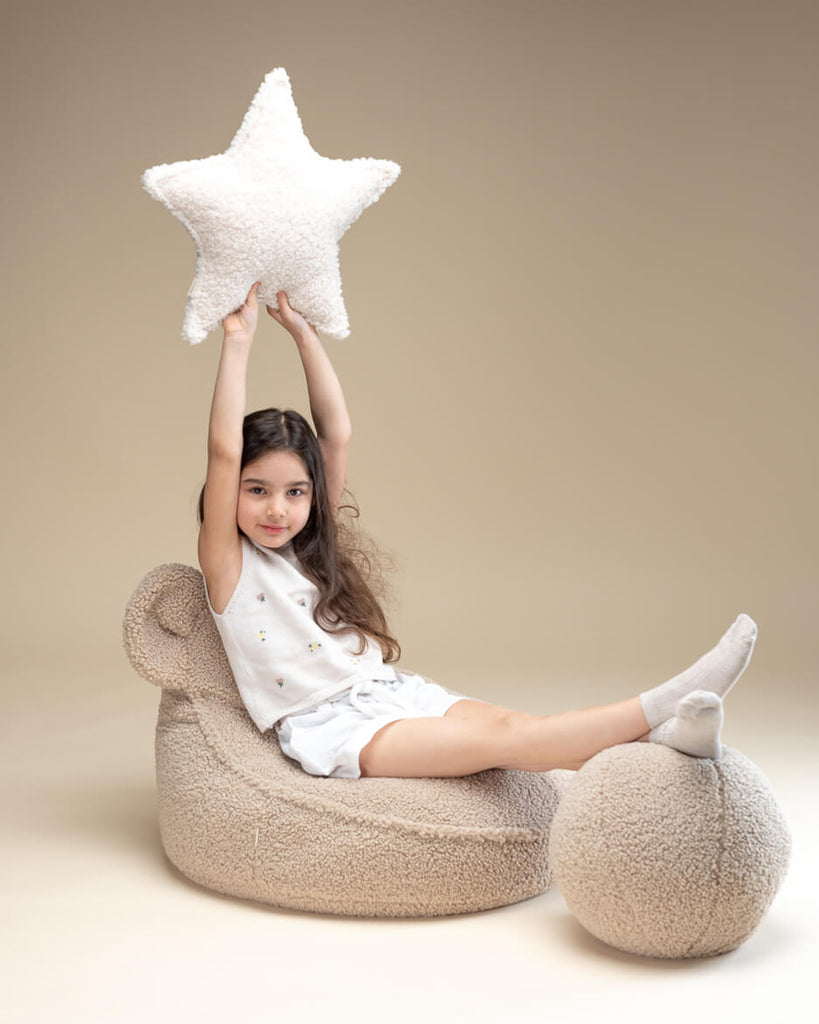 Meisje op teddy stoeltje met teddy bal kussen in biscuit kleur. De neutrale tint maakt het kussen een mooie en veilige keuze voor kinderen.