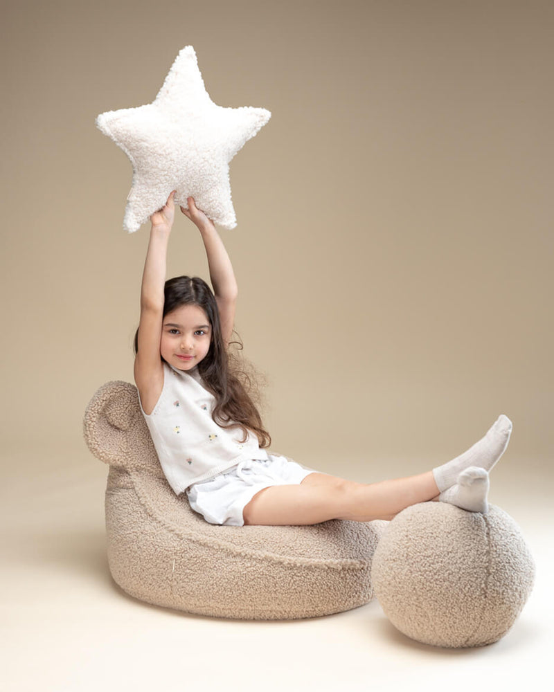 Meisje op teddy stoeltje met teddy bal kussen in biscuit kleur. De neutrale tint maakt het kussen een mooie en veilige keuze voor kinderen.