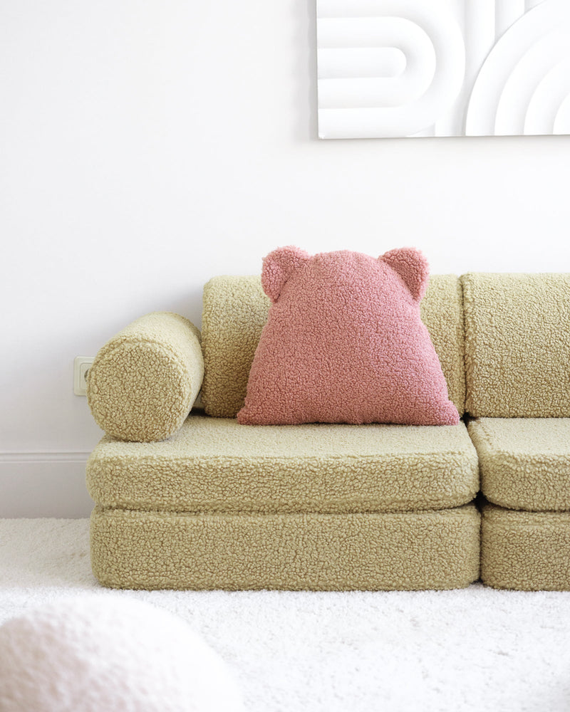 Roze teddy kussen met oortjes, van Wigiwama. Het sierkussen ligt op een kinderbank van hetzelfde merk.