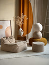Wigiwama teddy sierkussen in beige kleur als decoratief accent op een bijpassende poef en zitzak. Veilig, zacht en stijlvol in ieder interieur.