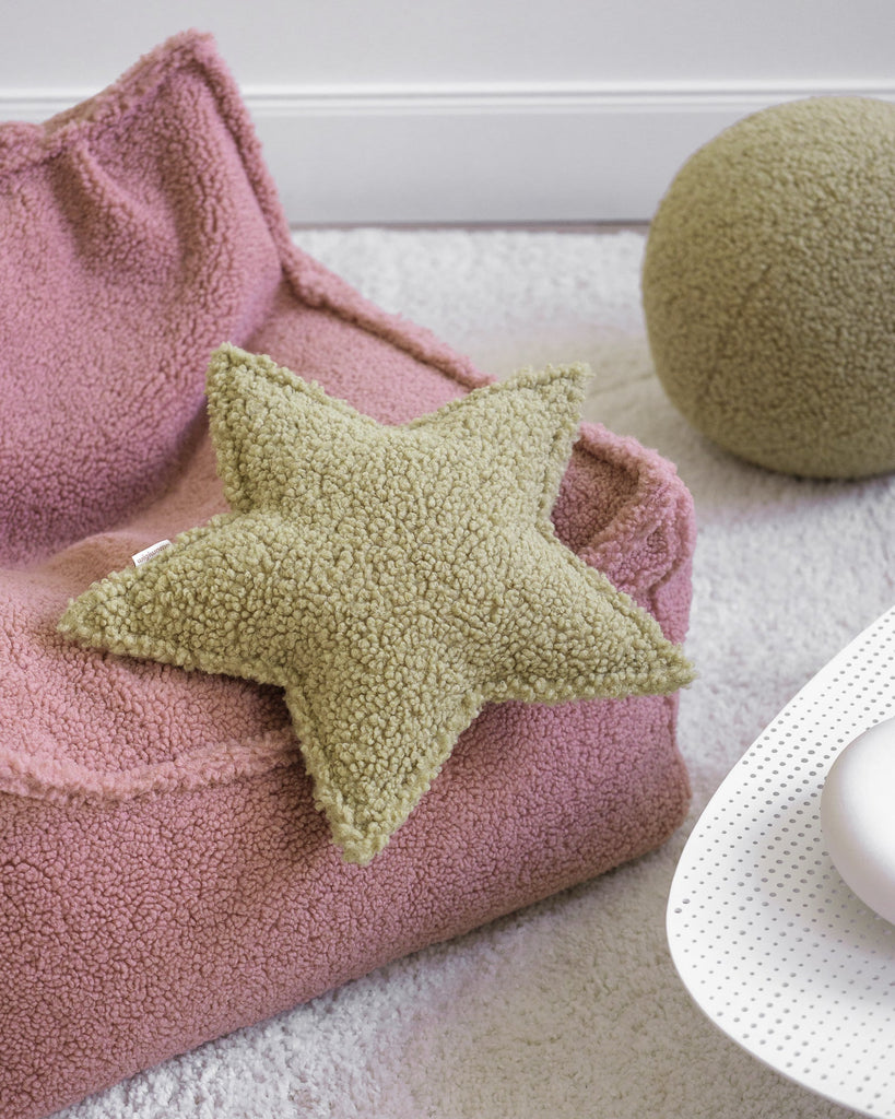 Het stervormige sierkussen van Wigiwama in de kleur matcha – een zachte, natuurlijke groentint – ligt op een roze zitzak en voegt warmte toe aan het ruimte-thema interieur.
