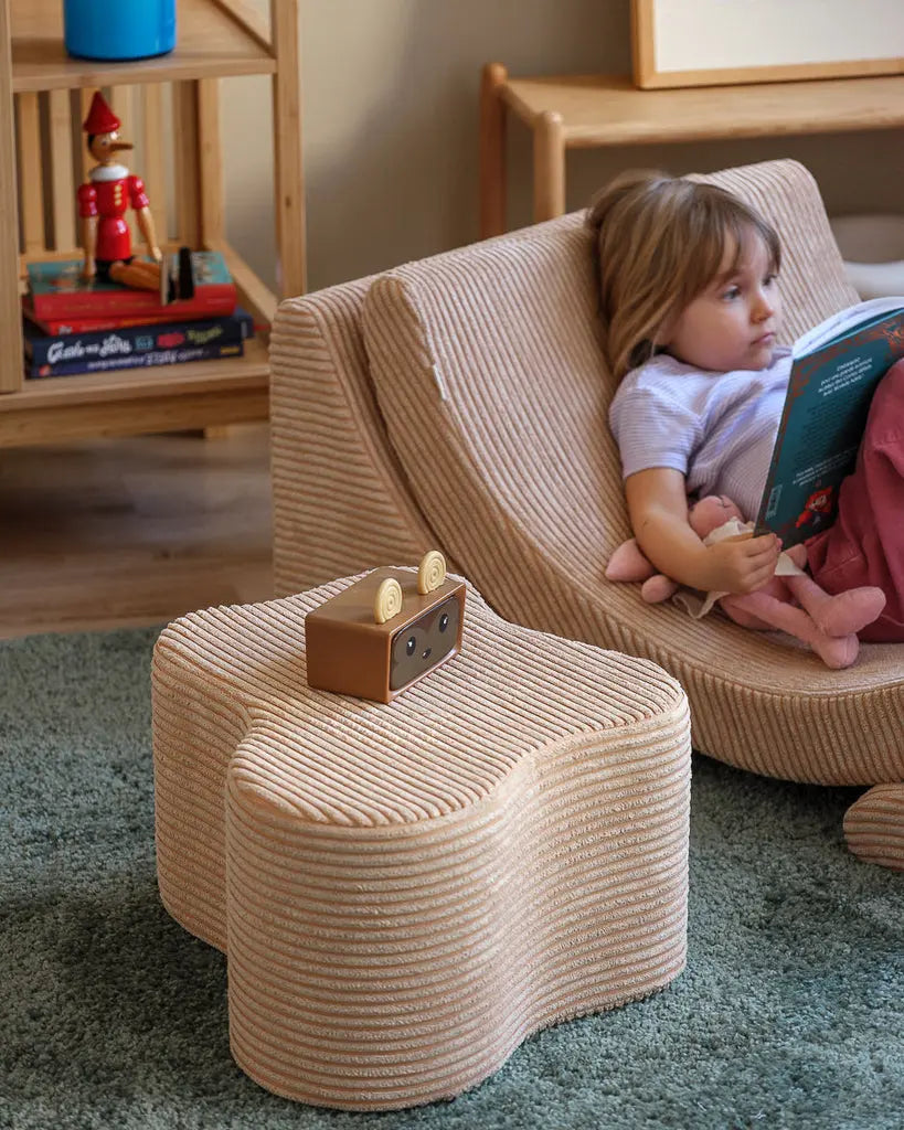 Kindje wat lekker languit in de Moon loungestoel voor kinderen ligt, met er naast de organisch gevormde Cloud wolken poef als tafeltje