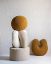 Het biscuitkleurige teddy sierkussen in U-vorm, stijlvol gecombineerd met andere vormen. Een speelse en creatieve toevoeging aan de kinderkamer die comfort en Scandinavisch design samenbrengt.