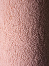 Close-up van de OEKO-TEX® gecertificeerde teddystof in guava pink kleur. Laat de zachte, pluizige structuur zien van het roze Wigiwama sierkussen in balvorm.