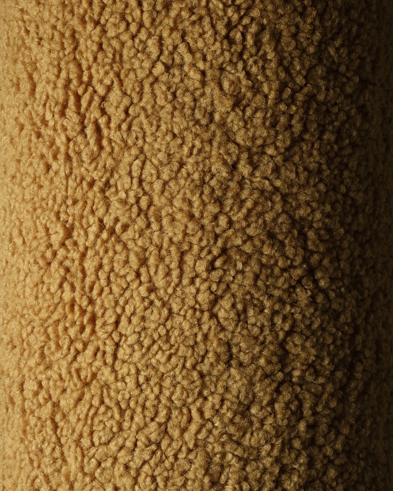 Close-up van de OEKO-TEX® gecertificeerde teddystof in maple kleur van het okergele Wigiwama sierkussen. Laat de zachte en veilige structuur van de stof zien.