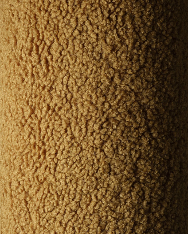 Close-up van de OEKO-TEX® gecertificeerde teddystof in maple kleur van het okergele Wigiwama sierkussen. Laat de zachte en veilige structuur van de stof zien.