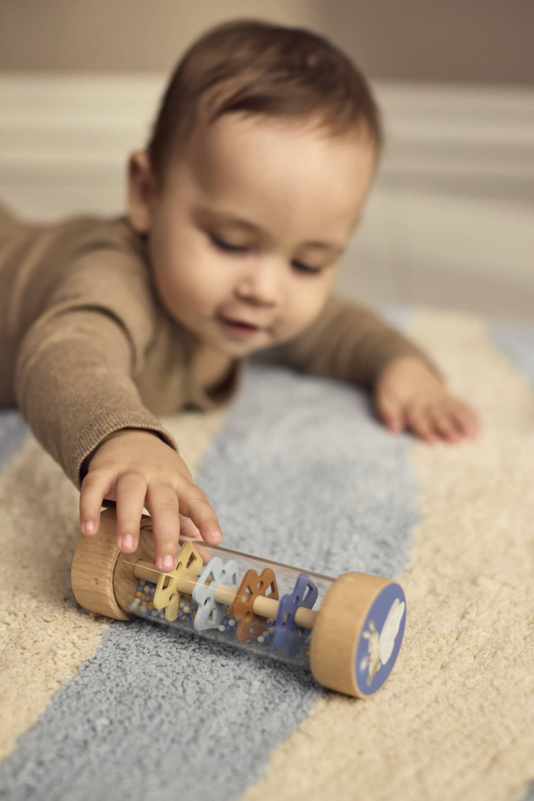 Baby ontdekt de houten rainmaker uit de sensorische speelset van Filibabba. De rainmaker heeft bewegende kralen en het zachte, rustgevende geluid van regen.