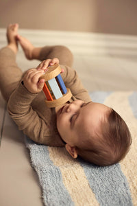 Baby speelt met de houten rammelaar uit de sensorische speelgoedset van Filibabba.