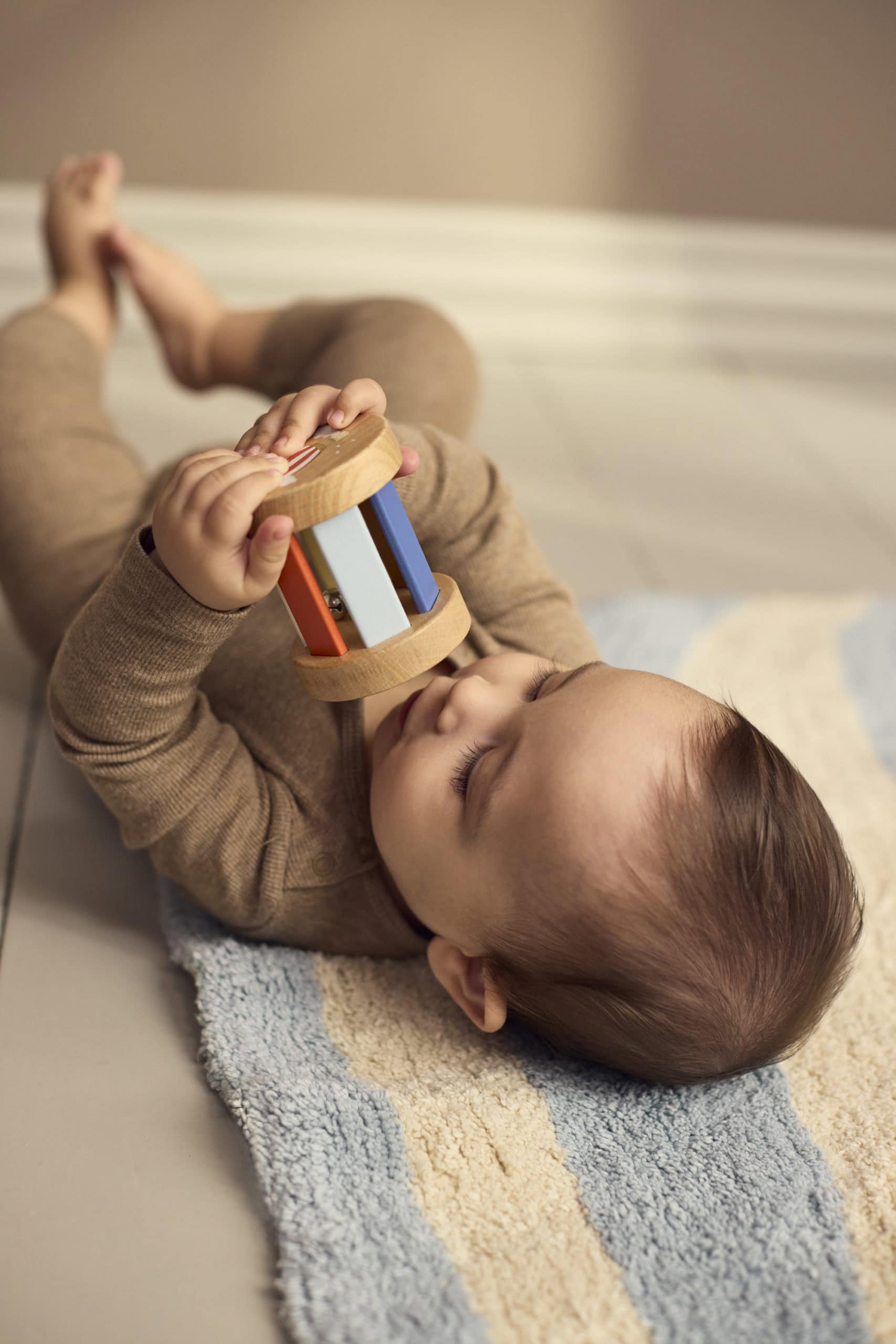 Baby speelt met de houten rammelaar uit de sensorische speelgoedset van Filibabba.