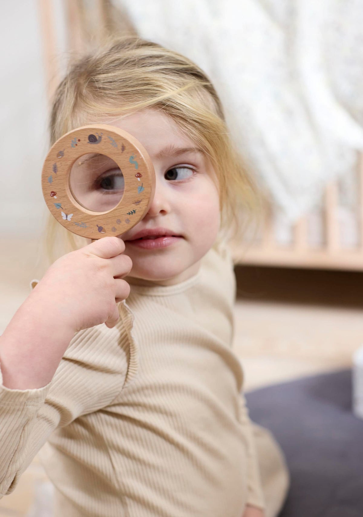 Meisje dat door het houten vergrootglas uit de ontdekkingsset van Filibabba kijkt.