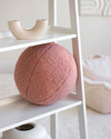 Het roze Wigiwama teddy sierkussen in guava pink als stijlvolle eyecatcher op een witte open kast. Ideaal als speels én decoratief element.