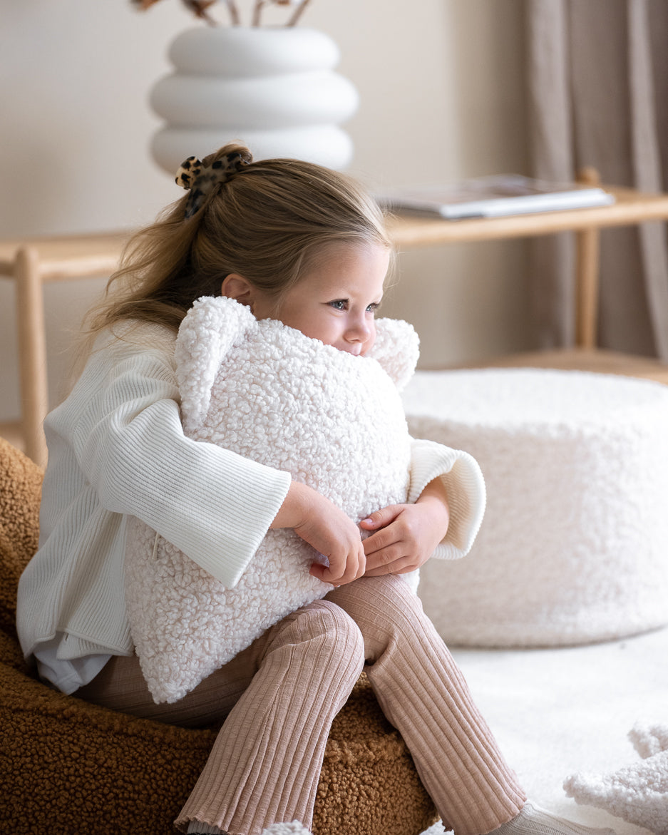 Een meisje knuffelt het ultra zachte Wigiwama berenkussen. Dankzij de OEKO-TEX® gecertificeerde teddystof is dit kussen niet alleen lief, maar ook veilig en duurzaam.
