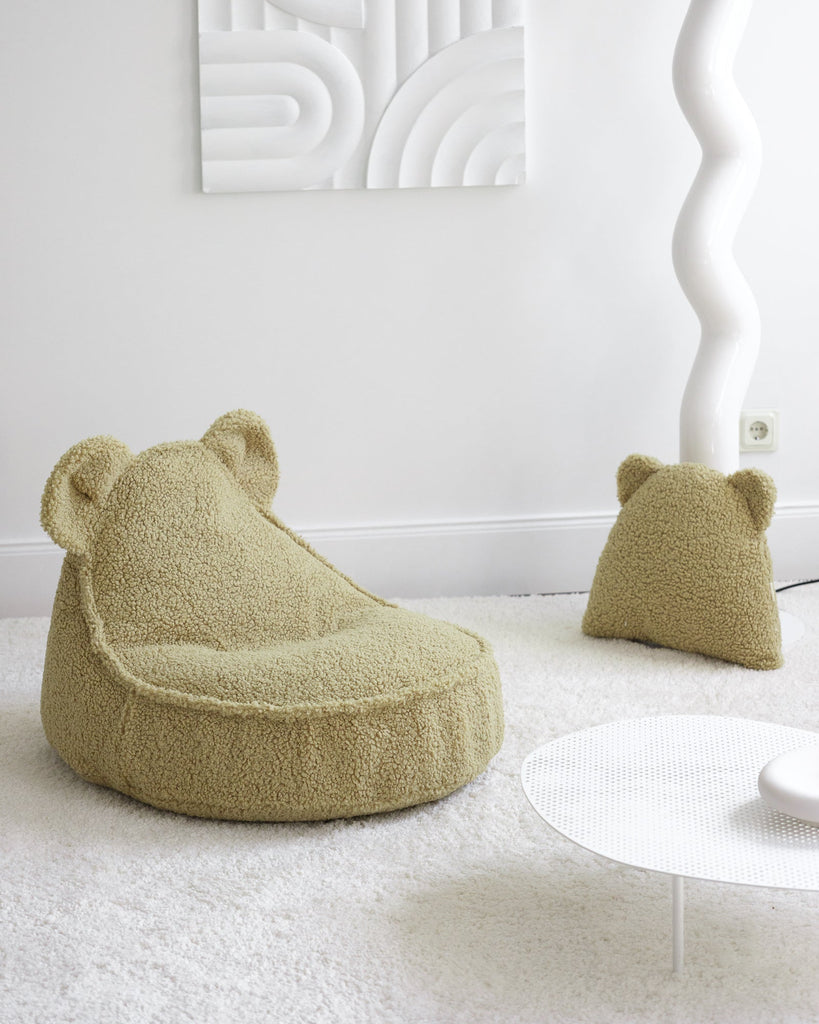 Een moderne, minimalistische kinderkamer met een matcha groene kinderfauteuil en bijpassend teddy beerkussen. De zachte, speelse vormen maken het een uitnodigende plek om te relaxen.