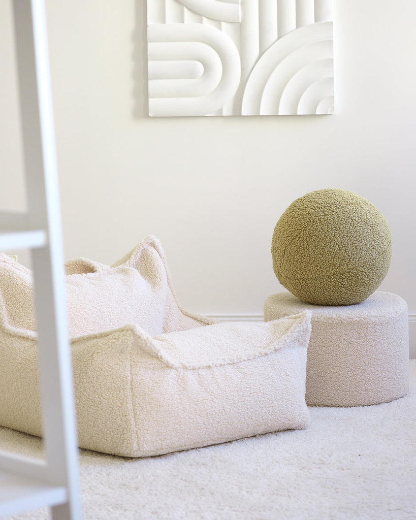 Neutrale kinderkamer met zachtgroen teddy sierkussen van Wigiwama. Perfect te combineren met andere teddystoffen voor een warme sfeer.