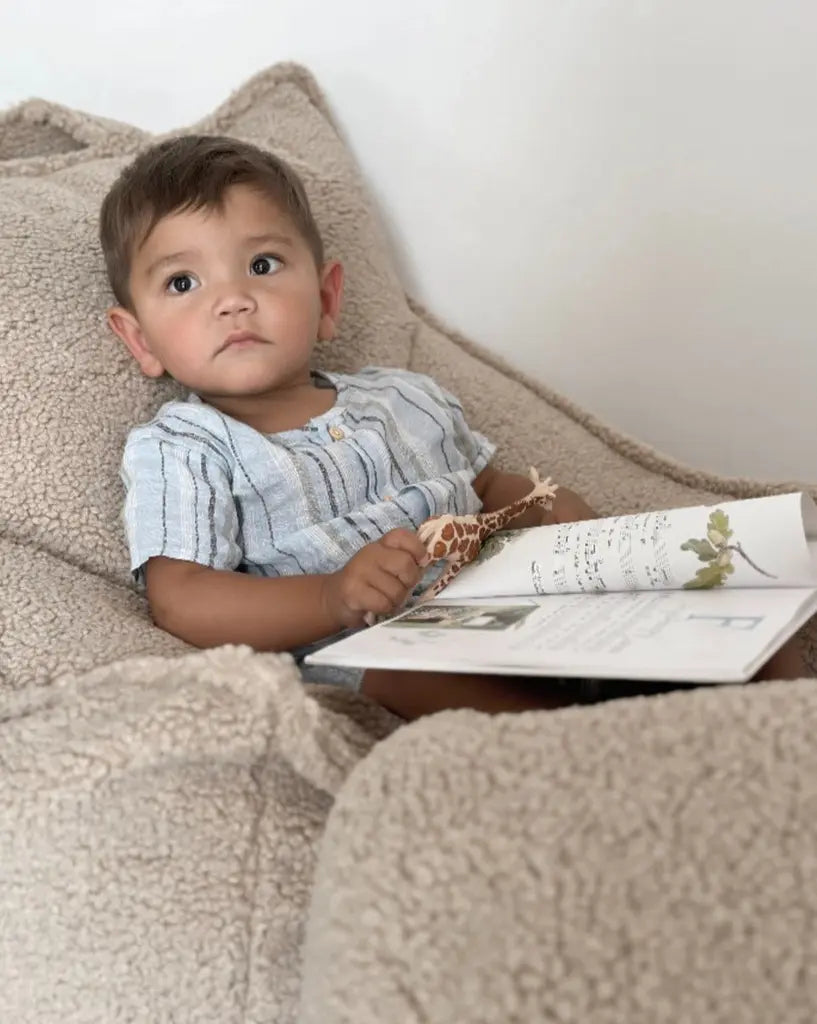 Kindje met een boek, ligt lekker te lezen in de zachte teddy lounge stoel van Wigiwama