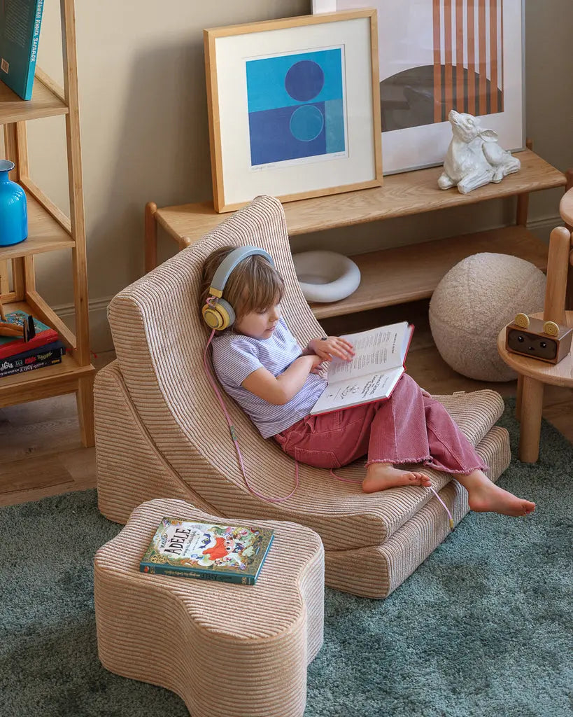 Kindje wat heerlijk een boekje zit te lezen in de Wigiwama kinder loungestoel. Op de wolken poef liggen nog meer leesboekjes