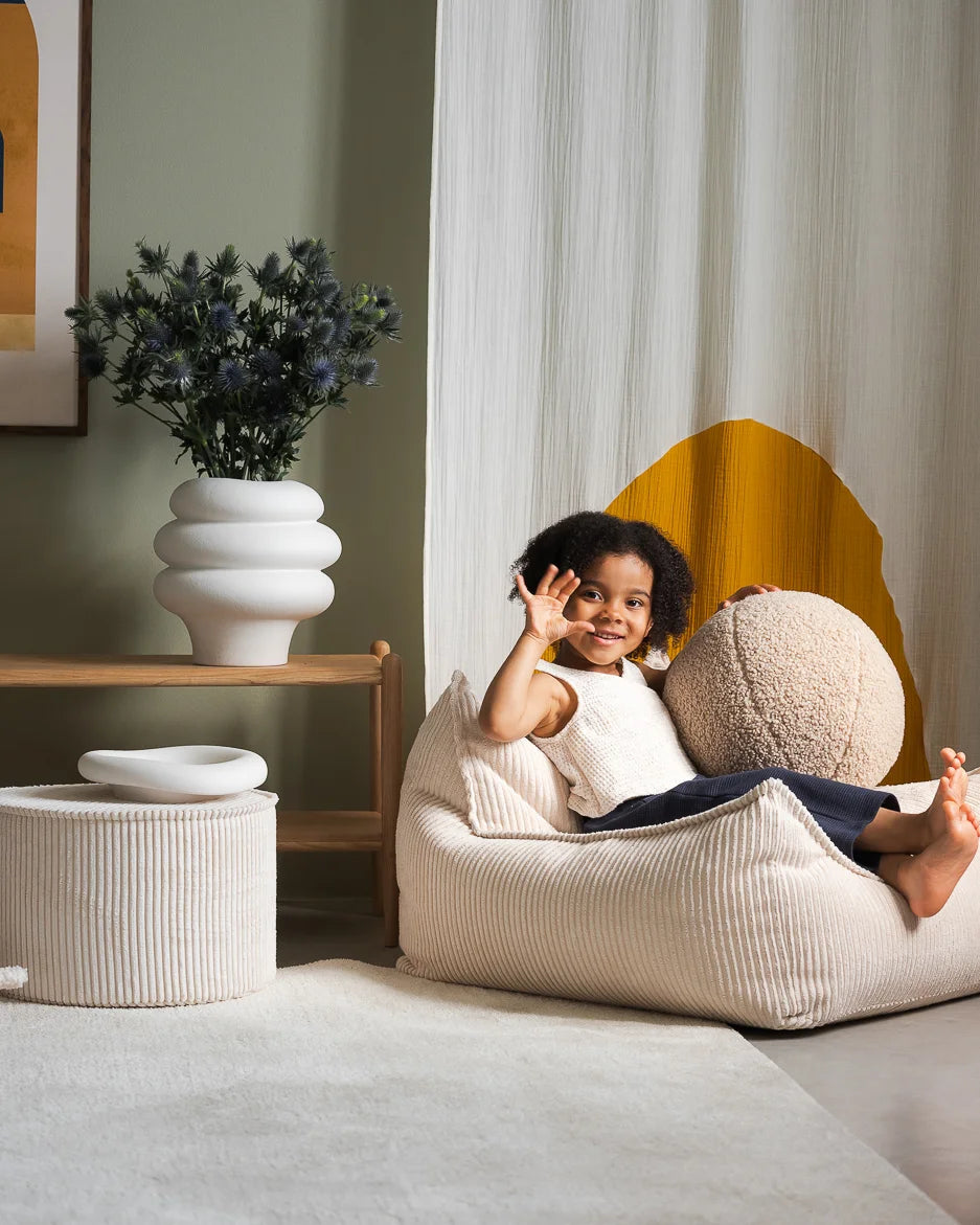 Lief kindje op een Wigiwama loungestoel voor kinderen, gecombineerd met een ribstof poef en een teddy bal van hetzelfde merk