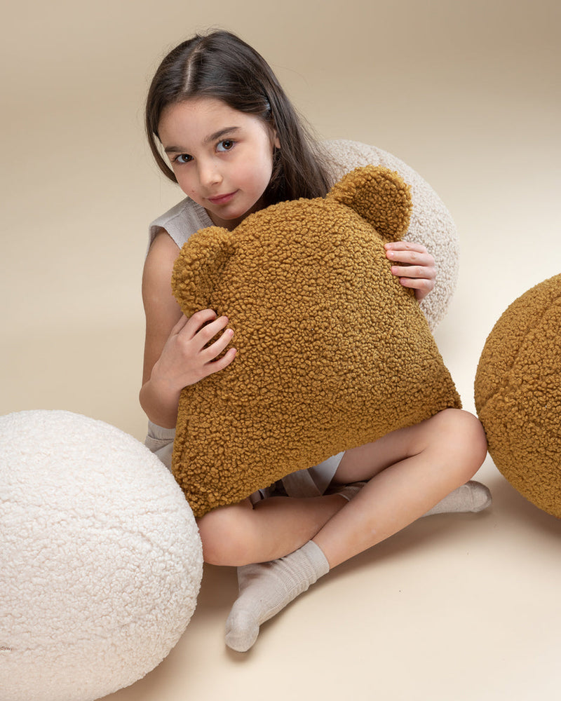 Kind met zachte teddy kussens van Wigiwama, waaronder de bal in cream kleur. Comfortabel, veilig en uitnodigend voor rust of spel.