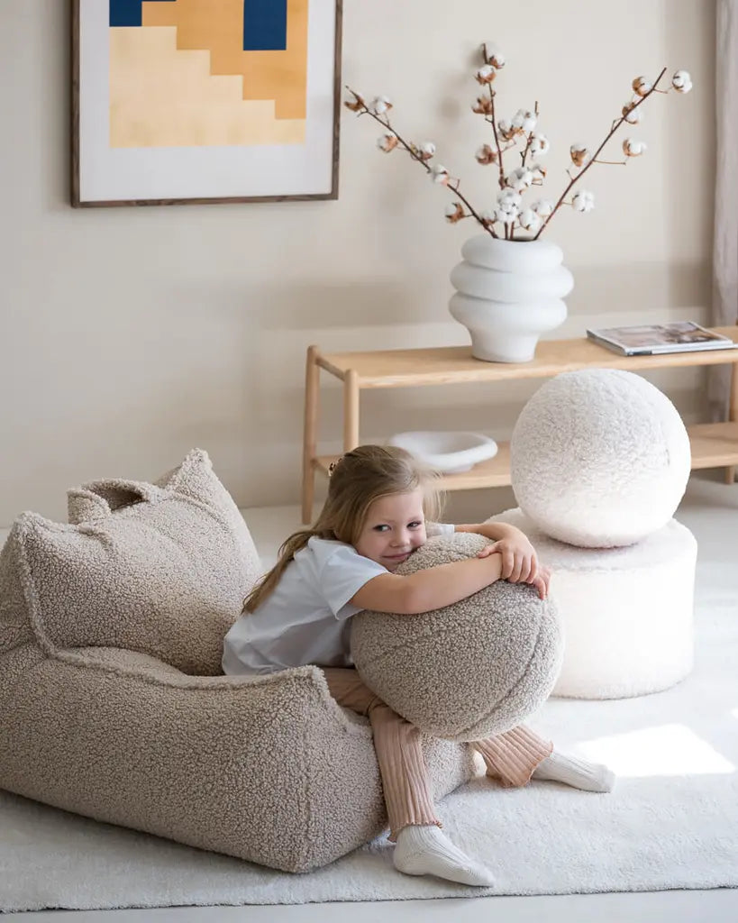 Een meisje wat heerlijk zit op de teddy zitzak of lounge stoel van Wigiwama, in haar handen heeft ze een grote teddy speelbal van hetzelfde merk