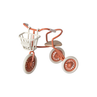 Voorbeeld van een koraalrood driewielrtje met het wit metalen fietsmandje voorop geklikt.