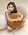 Kind met 3 grote teddy bal sierkussens van Wigiwama om zich heen.