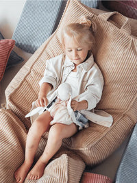 Meisje met blond haar knuffelt met teddybeer in de zachte Brown Sugar zitzak van Wigiwama