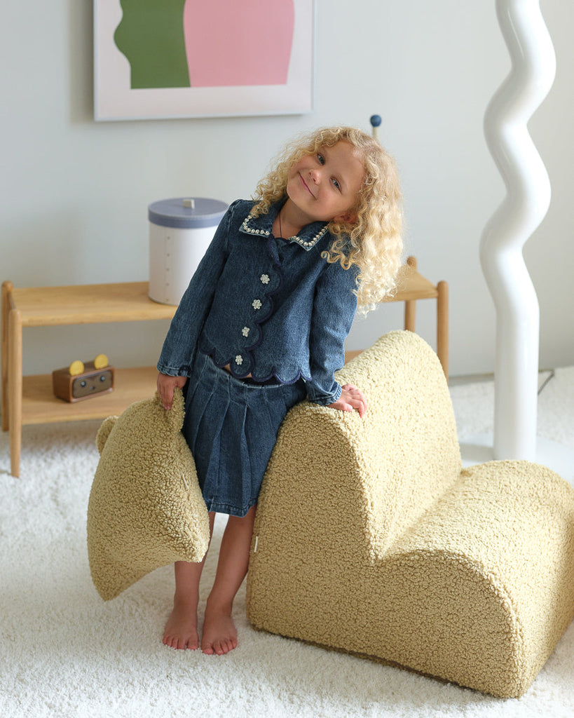 Een vrolijk kind met het teddy beerkussen in matcha – perfect passend bij de speelse kinderfauteuil in dezelfde zachte teddystof. Ideaal voor een knusse speelhoek of leesmomentje in de kinderkamer.