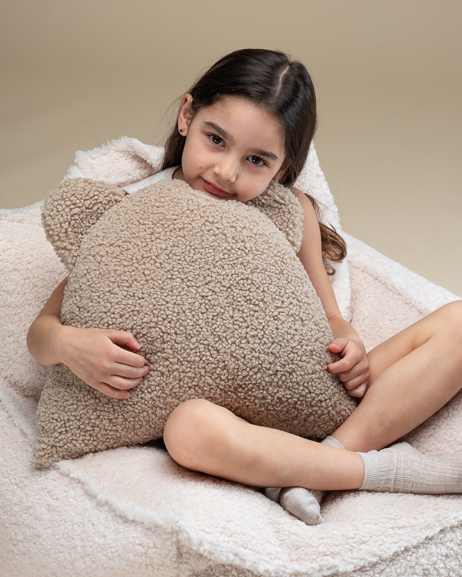 Knusse sfeer met een meisje dat het teddy beren kussen omarmt. De zachte, OEKO-TEX® gecertificeerde stof en stevige vulling maken dit kussen een favoriet rustplekje in elke kinderkamer of speelhoek.