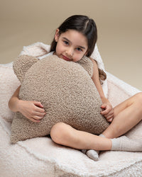Knusse sfeer met een meisje dat het teddy beren kussen omarmt. De zachte, OEKO-TEX® gecertificeerde stof en stevige vulling maken dit kussen een favoriet rustplekje in elke kinderkamer of speelhoek.