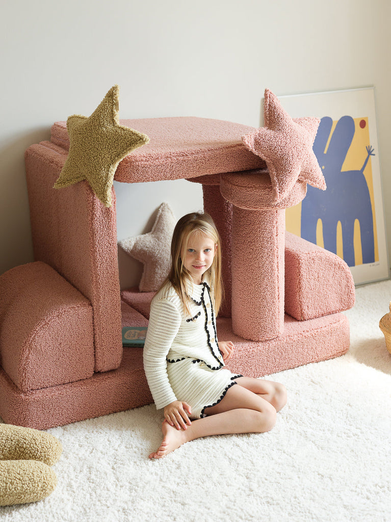 Speelse kinderkamer met roze speelmeubel en stervormige sierkussens van Wigiwama in de kleur matcha – een zachte groentint die prachtig contrasteert met pastelkleuren.