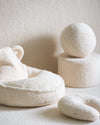 Sfeervol interieur in ton-sur-ton stijl, met het Wigiwama U-vorm kussen in cream wit als zacht en ondersteunend accent – perfect voor knusse leesmomentjes of ontspanning. Gecombineerd met een schattige zitzak met berenoortjes, een poef en een sierkussen in de vorm van een bal.