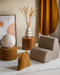 Het Wigiwama teddy sierkussen in maple geel siert deze stijlvol ingerichte kinderkamer met nog meer Wigiwama kindermeubels, een stoel, een poef en een zachte bal. Het zachte OEKO-TEX® teddykussen met beeroortjes is een speels en veilig decoratie-item dat perfect matcht met natuurlijke kleuren en houten accenten.