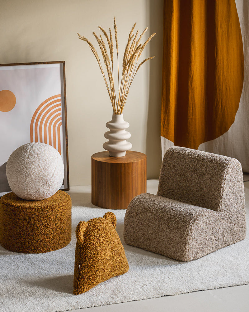 Het Wigiwama teddy sierkussen in maple geel siert deze stijlvol ingerichte kinderkamer met nog meer Wigiwama kindermeubels, een stoel, een poef en een zachte bal. Het zachte OEKO-TEX® teddykussen met beeroortjes is een speels en veilig decoratie-item dat perfect matcht met natuurlijke kleuren en houten accenten.