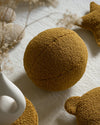 Close-up van het Wigiwama teddy sierkussen in maple kleur op een licht vloerkleed. Comfortabel, decoratief en gemaakt van veilige materialen voor kinderen.