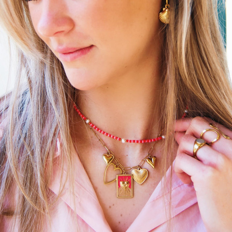 Oorbellen in de vorm van schelpjes, goudkleur. Op de foto gecombineerd met een bedelketting in rood en goud.