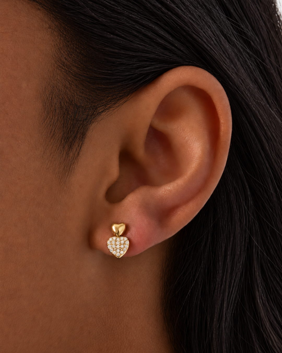 Detailfoto van de stekertjes oorbellen in stainless steel goud met witte strass steentjes. De oorbellen worden gedragen door een vrouw met donkere haren