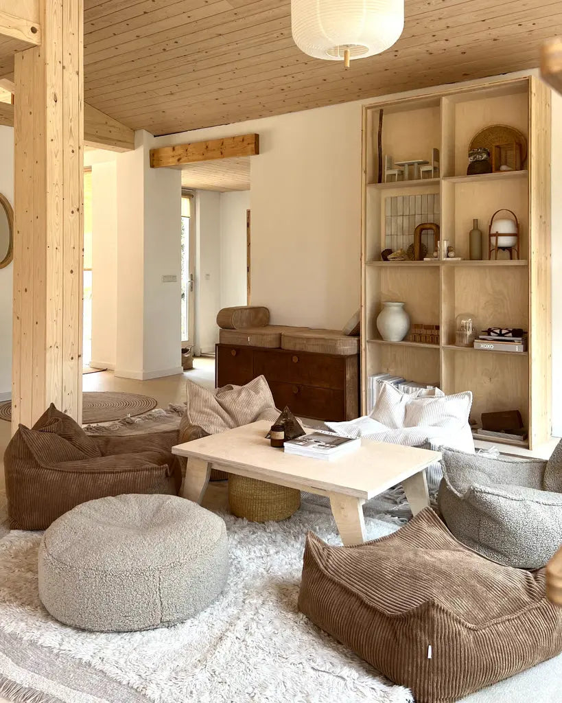 Sfeerbeeld van een woonkamer waarin de beige ronde poef als extra zitplek bij de salontafel fungeert.