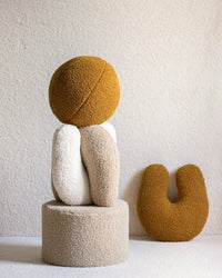 Creatieve opstelling met Wigiwama kussens in de vorm van een mensfiguur, met het okergele balvormige kussen als hoofd. Laat de veelzijdigheid van het teddy sierkussen zien.