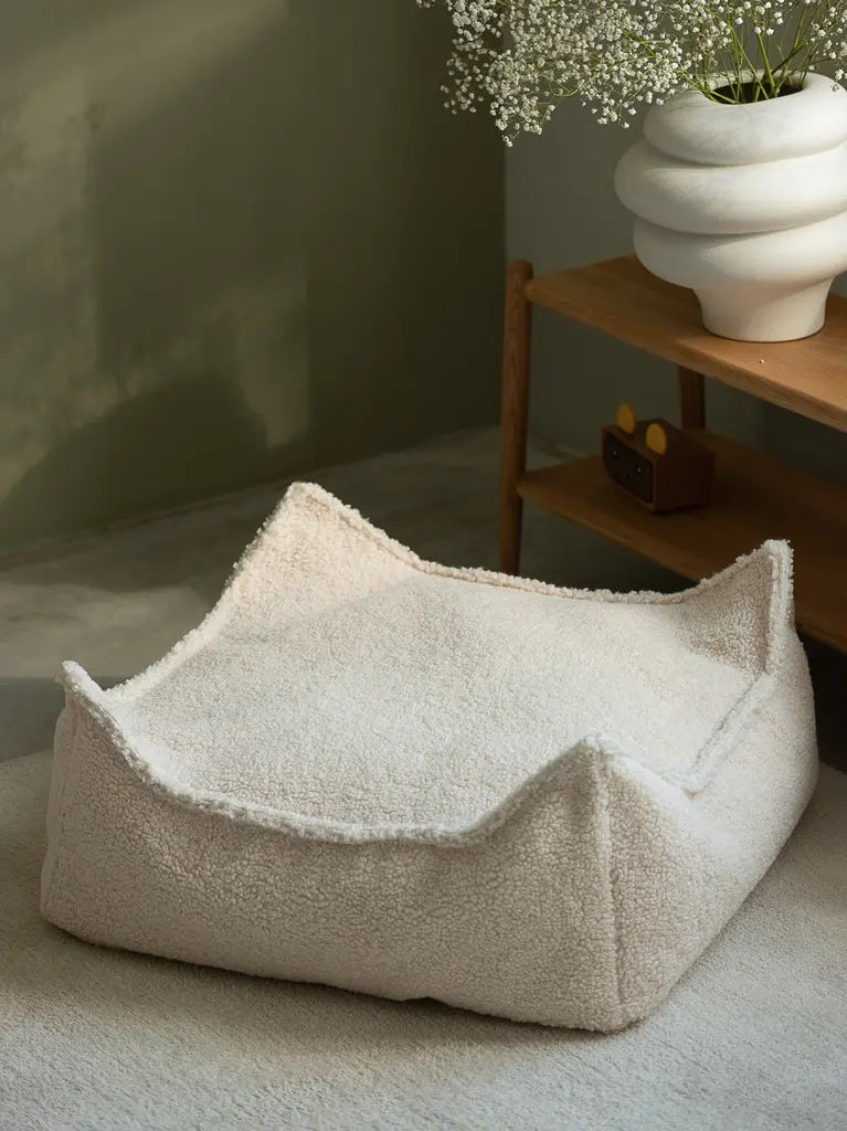 De vierkante poef van Wigiwama in een woonkamer met groene wand en houten tafeltje