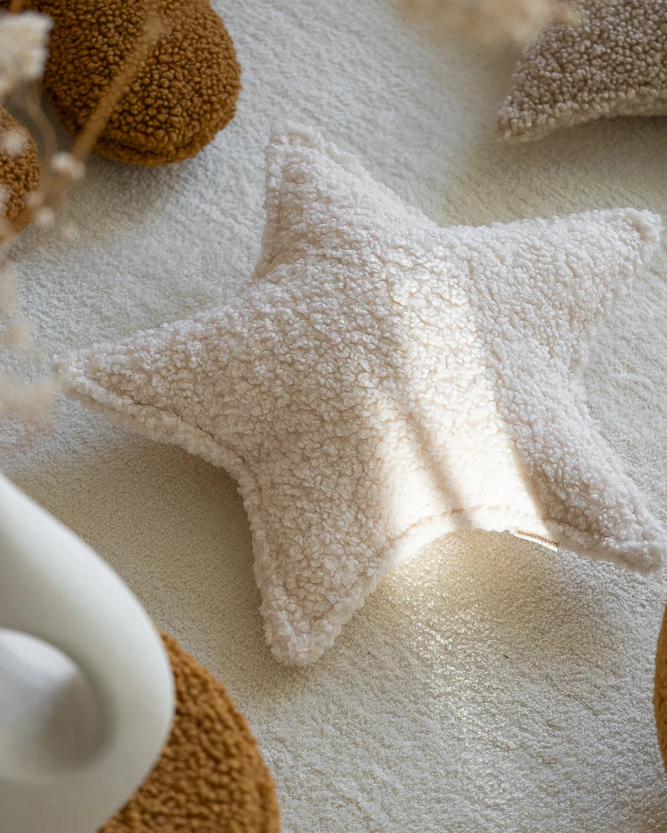 Het Wigiwama teddy sierkussen in stervorm straalt in zacht zonlicht – een warme en knuffelbare toevoeging aan elke kinderkamer.
