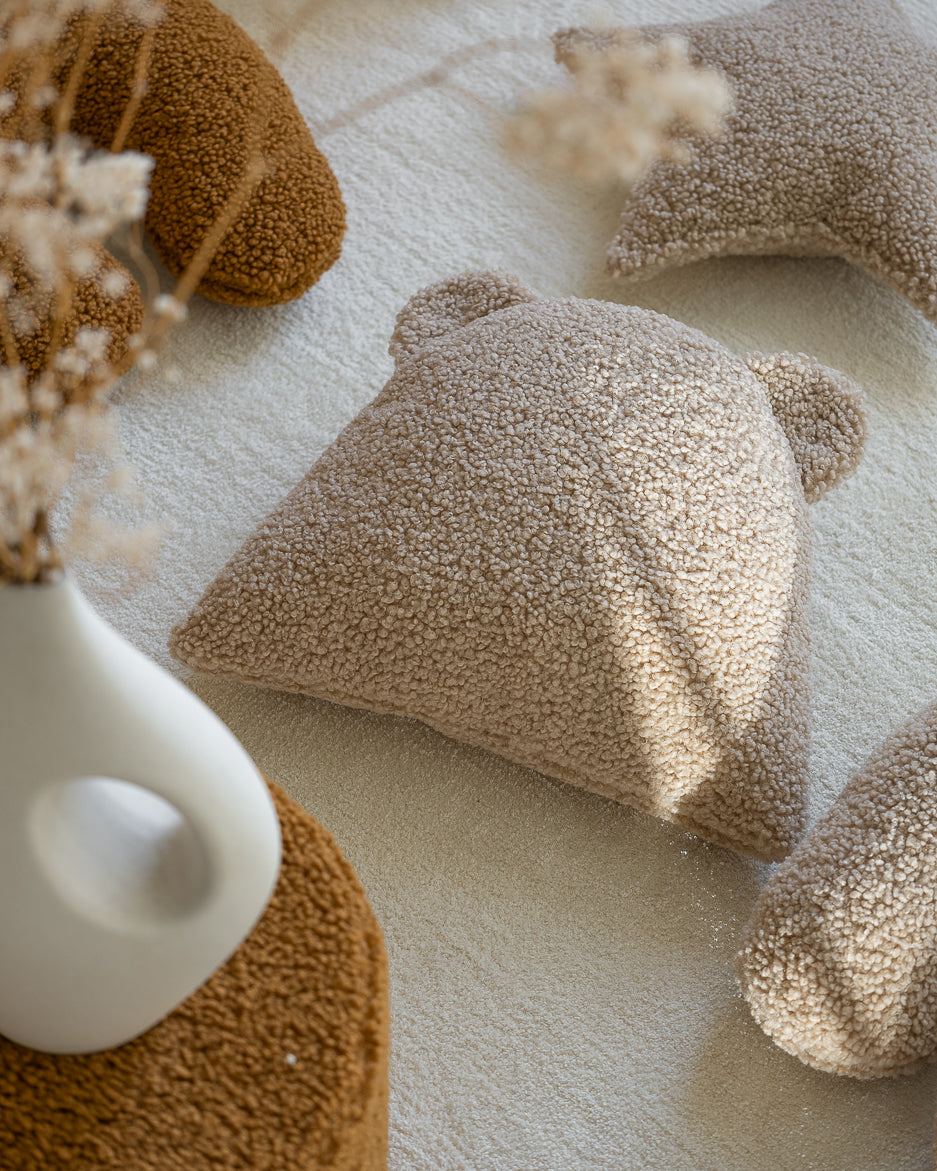 Het teddy beerkussen ligt uitnodigend in een warm interieur. Perfect als kinderkamer decoratie, dit duurzame en milieuvriendelijke kussen zorgt voor een zachte, speelse sfeer in huis.