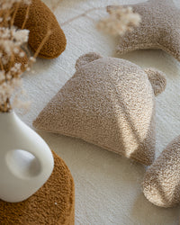 Het teddy beerkussen ligt uitnodigend in een warm interieur. Perfect als kinderkamer decoratie, dit duurzame en milieuvriendelijke kussen zorgt voor een zachte, speelse sfeer in huis.