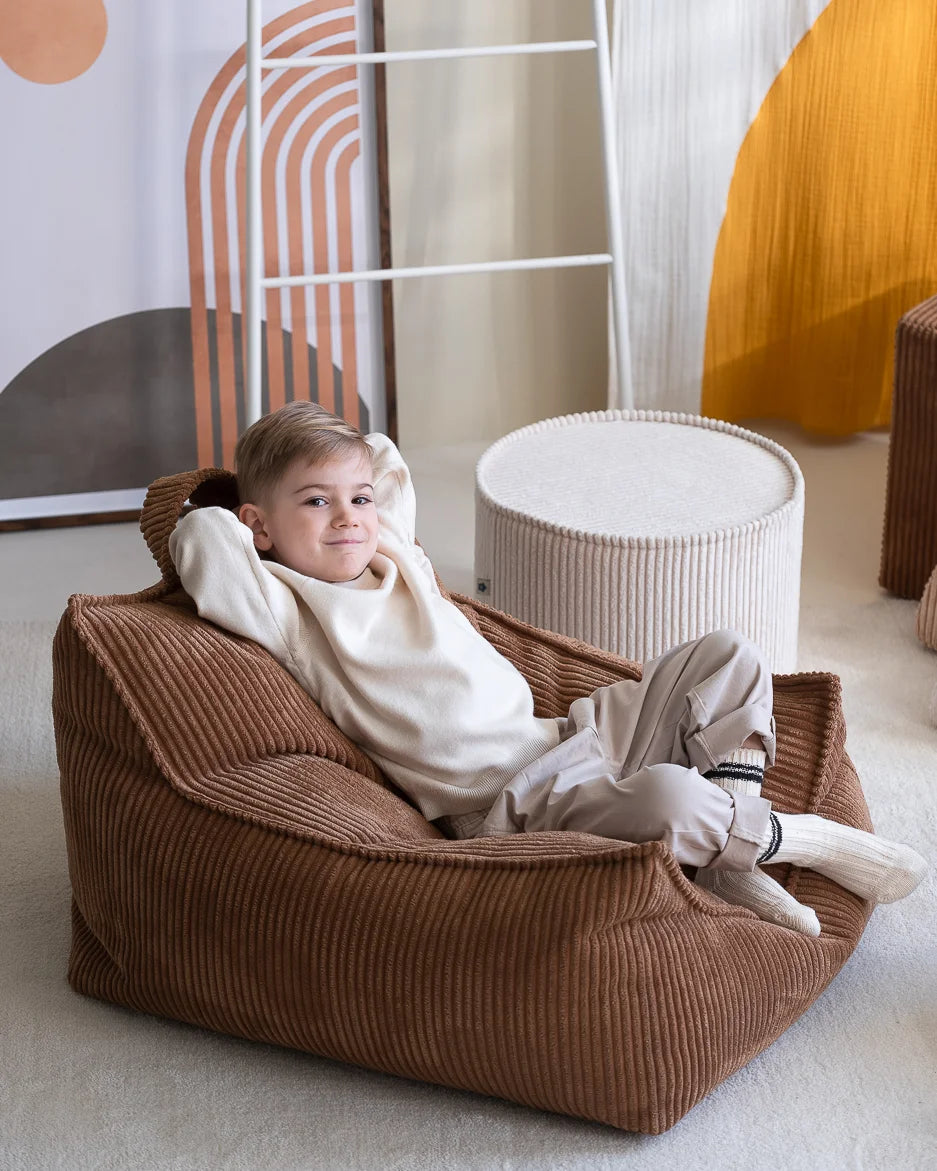 Kindje op een bruine ribstof zitzak, gecombineerd met de marshmallow poef uit dezelfde serie van Wigiwama. Hier gaat je kindje blij van worden!