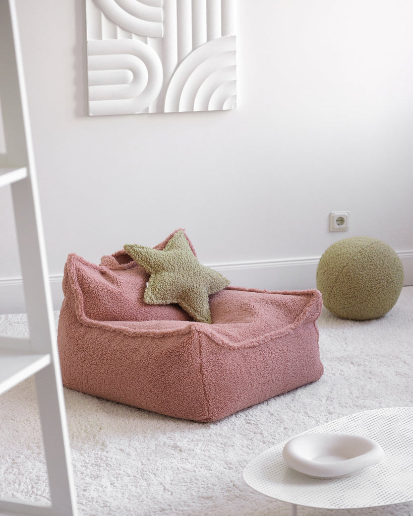 Het Wigiwama stervormige kussen in matcha – een subtiele zachtgroene tint – ligt op een roze teddy zitzak en vormt een rustig, decoratief accent in de speelhoek.