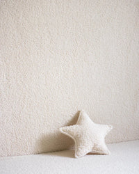 Stervormig sierkussen in cream teddystof van Wigiwama als decoratief accent tegen een zachte muur – perfect voor het ruimte-thema in de kinderkamer.