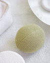 Het groene teddy kussen van Wigiwama in matcha kleur staat op een licht vloerkleed in een strak vormgegeven ruimte. Stijlvolle én kindvriendelijke toevoeging aan het interieur.